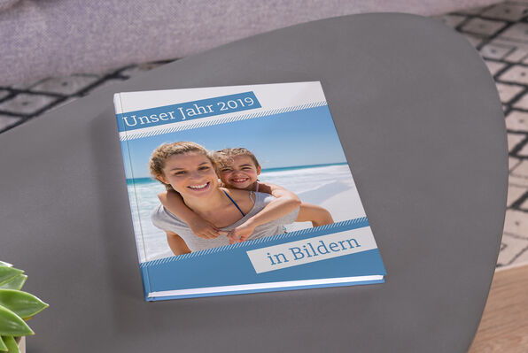 a large A4 portrait photo book open to a full page spread of a families adventure