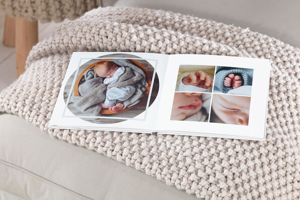 Square photo book open to pages with photos of a baby